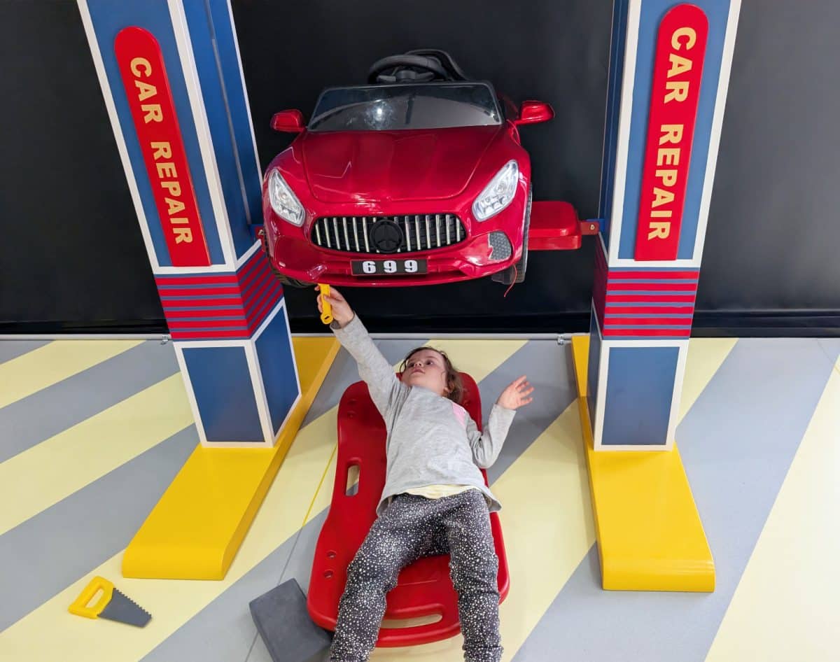 NEW Landing Play Centre Altona North 5 Child playing in a “car repair” role-play station with a toy car on a lift and plastic tools at Landing Play Centre Altona North