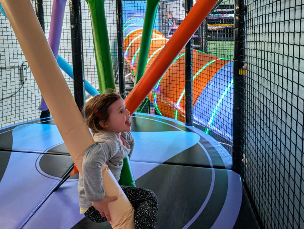 NEW Landing Play Centre Altona North 10 Child climbing through a netted indoor play area with padded poles and soft flooring at Landing Play Centre Altona North