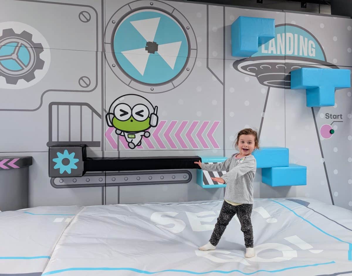 NEW Landing Play Centre Altona North 1 Young child standing on a padded soft-play landing mat in front of a space-themed wall at Landing Play Centre Altona North.